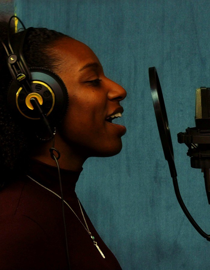 Latiesha Dukes singing into a studio microphone